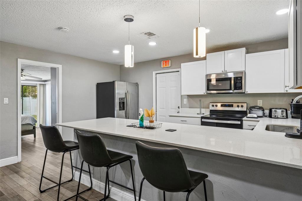 A kitchen features a white quartz island, black bar stools, and white cabinetry — 520 FAIRFAX LANE, APOLLO BEACH, FL