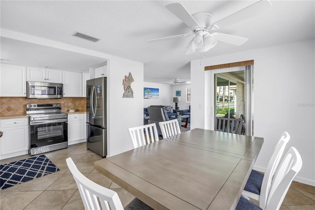 A kitchen with stainless steel appliances and a dining area with a wooden table — 6150 MIDNIGHT PASS ROAD UNIT V38, SARASOTA, FL
