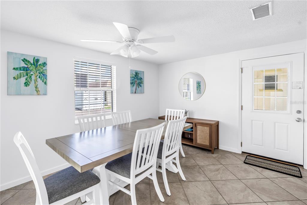 A dining room features a wooden table, white chairs, tile flooring, and a ceiling fan — 6150 MIDNIGHT PASS ROAD UNIT V38, SARASOTA, FL