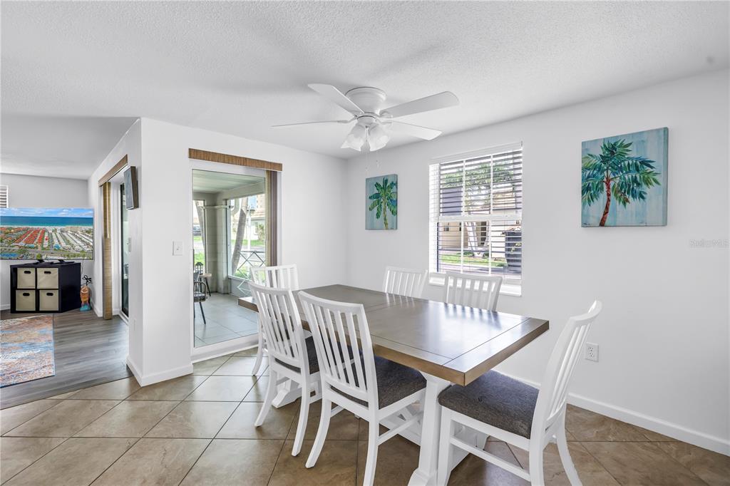A dining room with a white table, six chairs, tile flooring, and a ceiling fan — 6150 MIDNIGHT PASS ROAD UNIT V38, SARASOTA, FL
