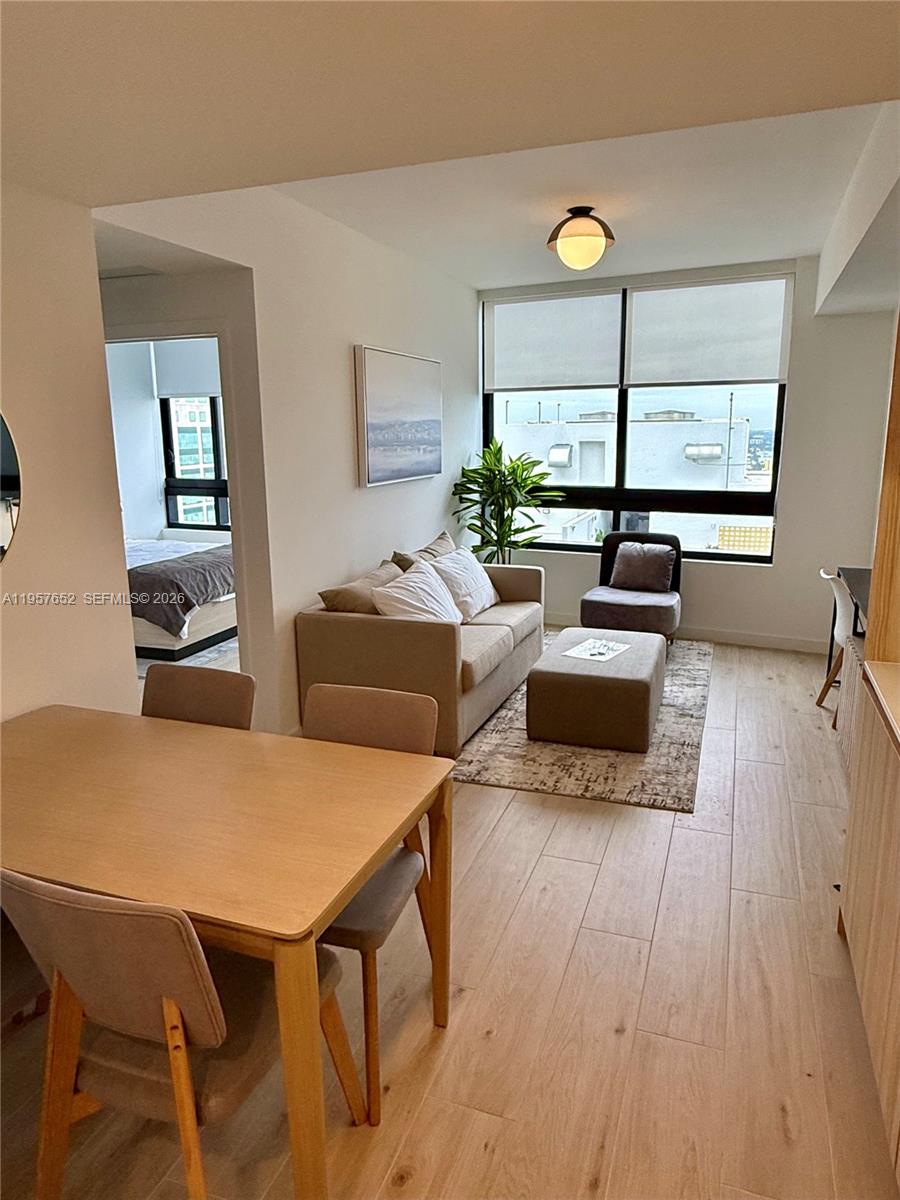 A living room and dining area feature light wood floors, neutral furniture, and large windows — 225 N Miami Ave # 3406, Miami FL 33128, MIAMI, FL