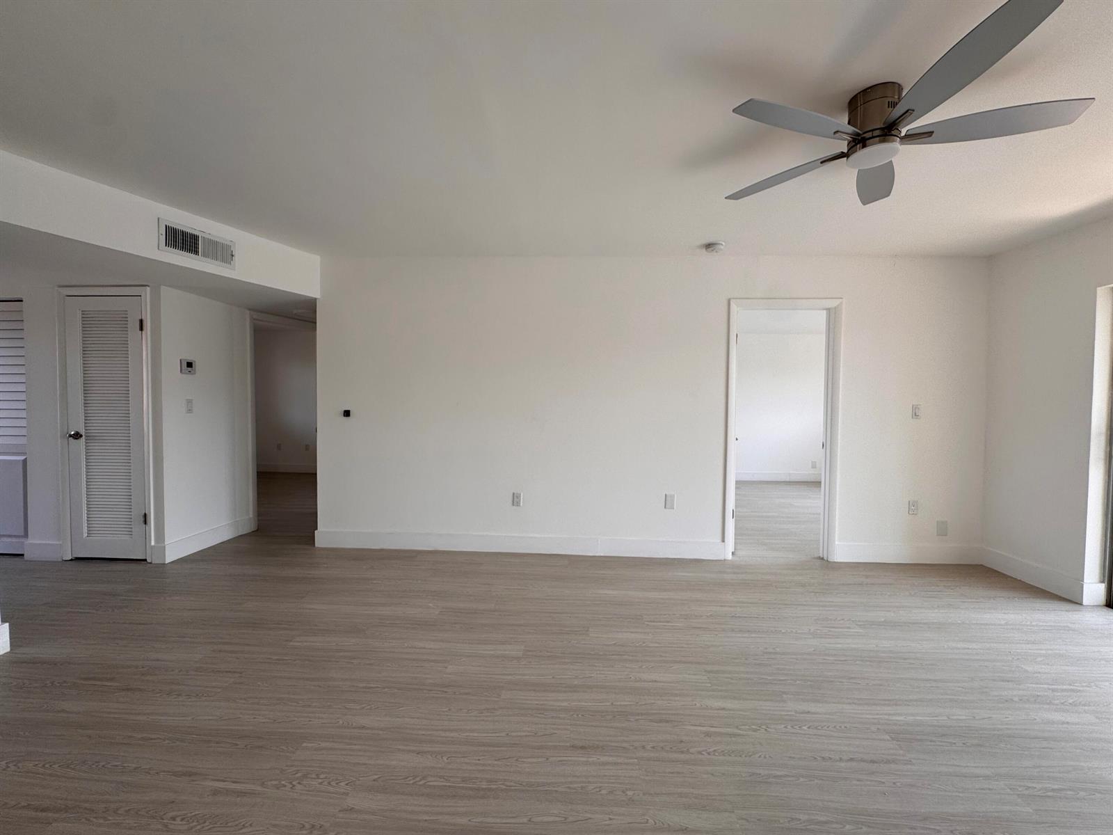 An empty room with light wood-look flooring, white walls, a ceiling fan, and two doorways — 2831 E Sunrise Lakes Drive E # 311, Sunrise FL 33322, SUNRISE, FL