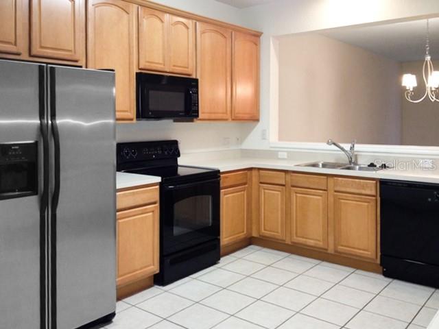 A kitchen features light wood cabinets, stainless steel appliances, and white tile flooring — 2551 STOCKTON DRIVE, SANFORD, FL