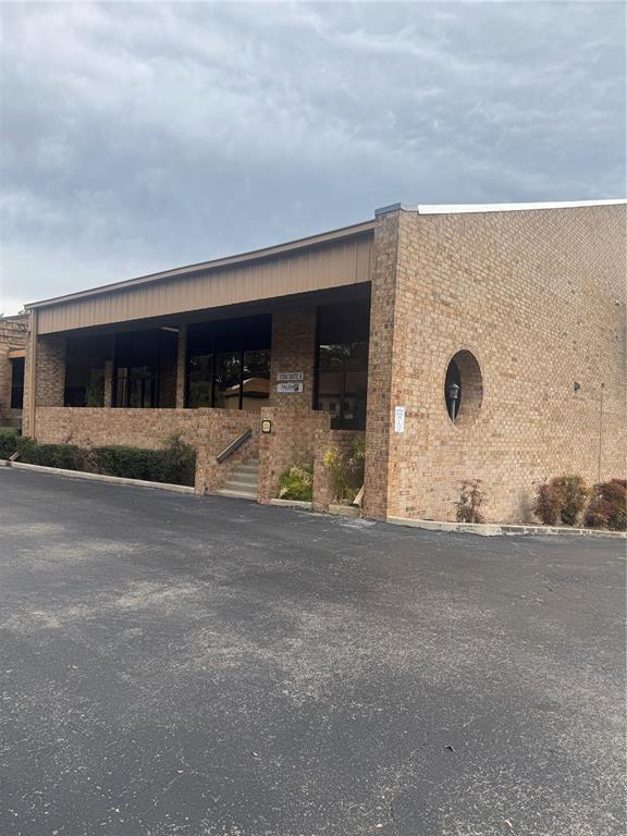 A low-rise brick commercial building features a recessed entrance with stairs and a circular window — 1204 NW 69TH TERRACE UNIT B, GAINESVILLE, FL