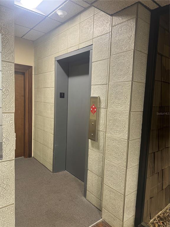 An elevator door is set within a wall covered in decorative, textured square tiles — 1204 NW 69TH TERRACE UNIT B, GAINESVILLE, FL
