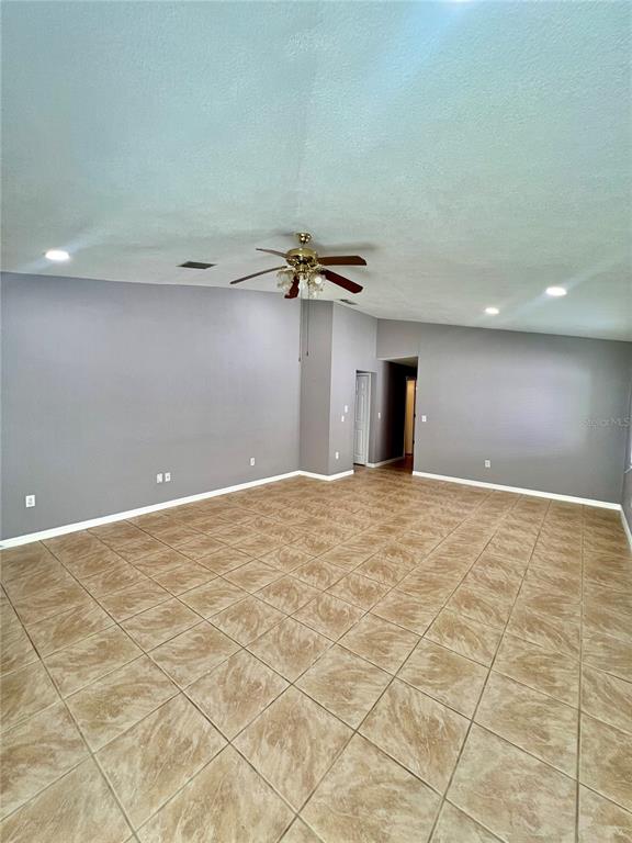 An empty room features gray walls, a vaulted ceiling with a fan, and tiled flooring — 409 ABIGAIL ROAD, PLANT CITY, FL