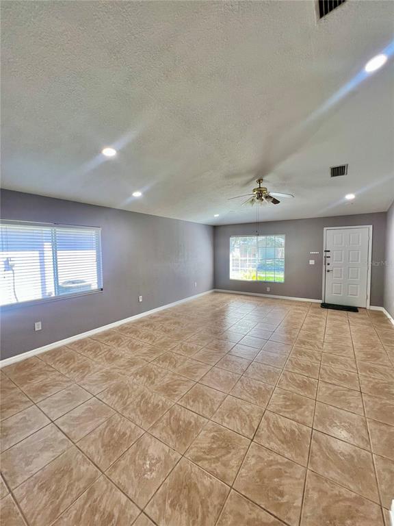 A spacious living room features light-colored tile flooring, gray walls, recessed lighting, and a ceiling fan — 409 ABIGAIL ROAD, PLANT CITY, FL