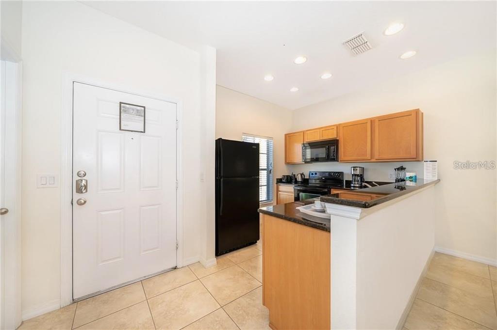A kitchen with light wood cabinets, black appliances, and a granite-topped breakfast bar — 3007 WHITE ORCHID ROAD, KISSIMMEE, FL
