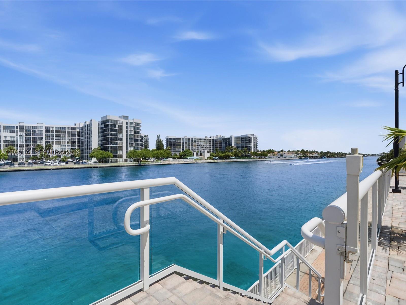 An outdoor terrace with a glass railing overlooks a wide canal and apartment buildings — 3000 S Ocean Dr # 718, Hollywood FL 33019, HOLLYWOOD, FL