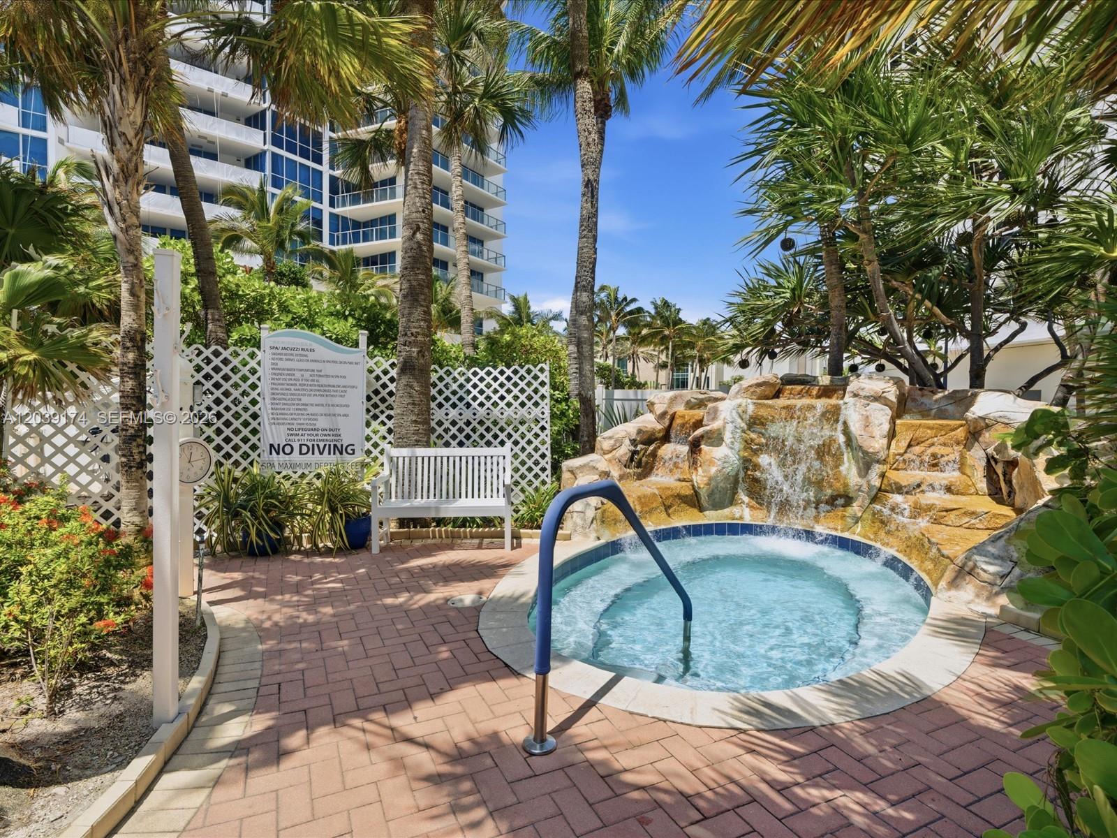 A hot tub with a rock waterfall feature sits on a brick patio near palm trees — 3000 S Ocean Dr # 718, Hollywood FL 33019, HOLLYWOOD, FL