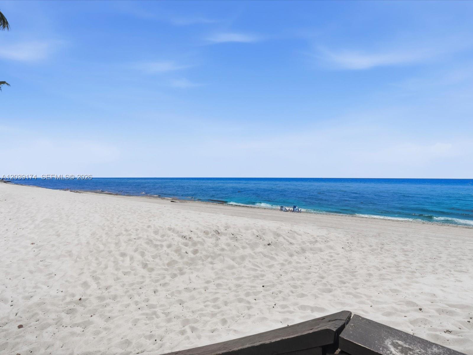 A view of a sandy beach meeting the blue ocean under a clear sky — 3000 S Ocean Dr # 718, Hollywood FL 33019, HOLLYWOOD, FL