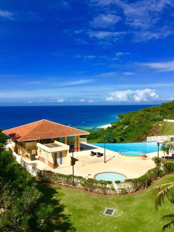 An elevated view shows a coastal clubhouse with a pool, hot tub, and ocean backdrop — 1 COND. PUERTA DEL MAR, AGUADILLA, PR