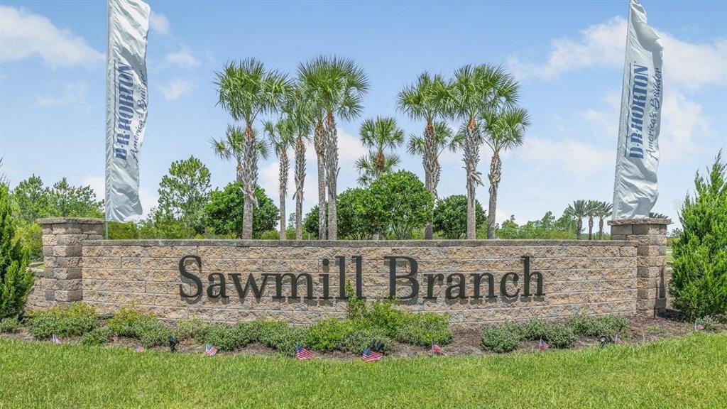 A stone monument sign for Sawmill Branch stands in a grassy area with palm trees — 166 SPRINGWOOD DRIVE, PALM COAST, FL