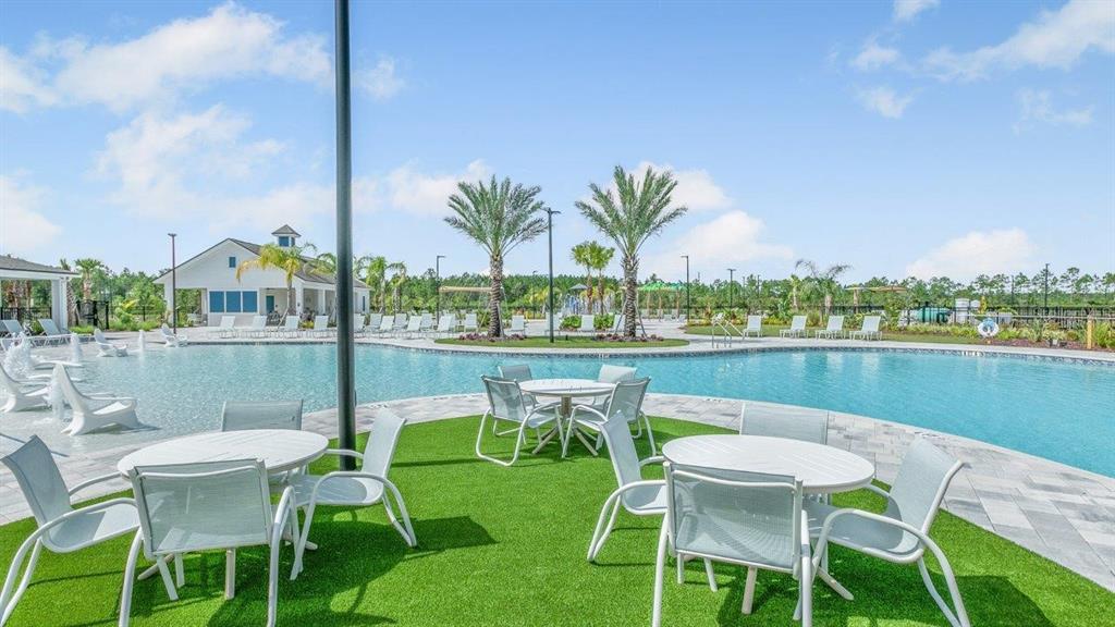A swimming pool with lounge chairs and patio tables on a green turf area — 166 SPRINGWOOD DRIVE, PALM COAST, FL