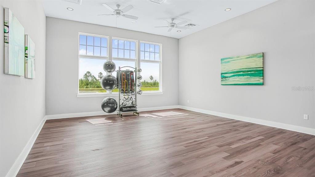 A bright exercise room features light gray walls, wood-look flooring, and a fitness equipment rack — 166 SPRINGWOOD DRIVE, PALM COAST, FL