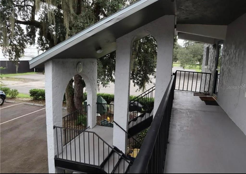 An exterior view of a covered balcony with white stucco arches and black metal railings — 220 N IDLEWOOD AVENUE UNIT 204, BARTOW, FL