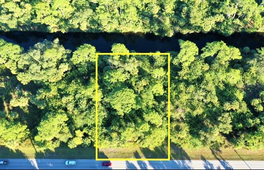 An aerial view shows a rectangular, wooded vacant lot bordering a road and a canal — 152 PRINEVILLE STREET, PORT CHARLOTTE, FL