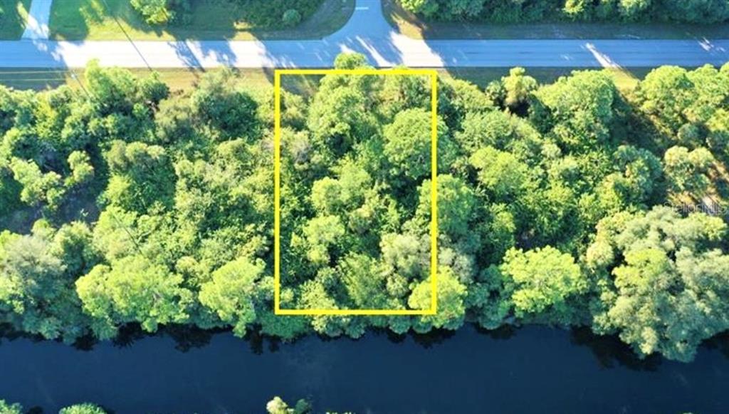 An aerial view shows a rectangular wooded lot situated between a road and a canal — 152 PRINEVILLE STREET, PORT CHARLOTTE, FL