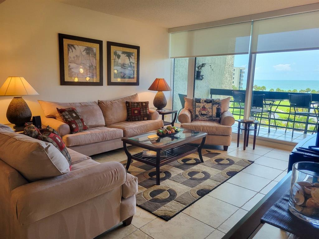 A living room with beige sofas, a patterned rug, and a balcony overlooking the ocean — 1105 GULF OF MEXICO DRIVE UNIT 402, LONGBOAT KEY, FL