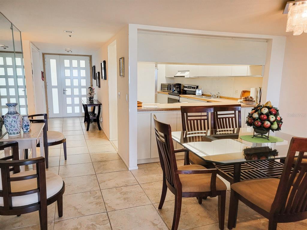 A dining area with a glass table and chairs sits adjacent to an open kitchen — 1105 GULF OF MEXICO DRIVE UNIT 402, LONGBOAT KEY, FL