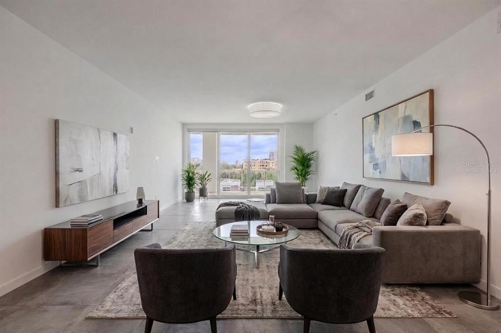A modern living room features a gray sectional sofa, two armchairs, and a glass coffee table — 920 N OSCEOLA AVENUE UNIT 703, CLEARWATER, FL