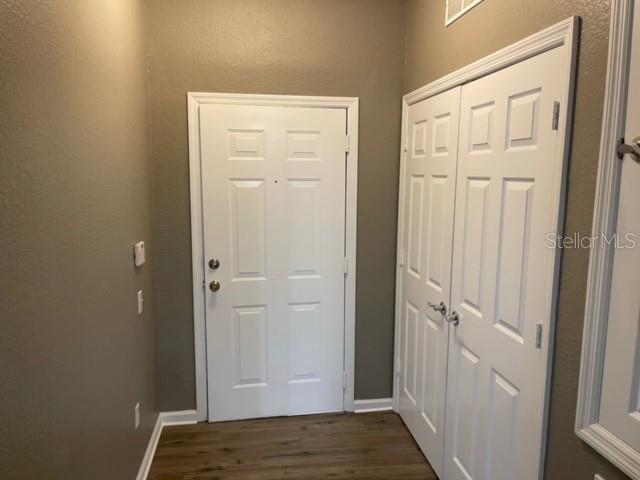 An entryway features a white front door, a white double-door closet, and wood-look flooring — 6434 CAVA ALTA DRIVE UNIT 406, ORLANDO, FL