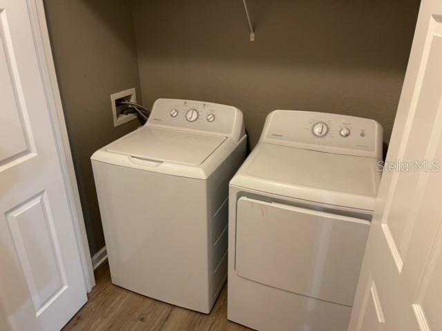 A white top-load washing machine and dryer sit side-by-side in a small laundry closet — 6434 CAVA ALTA DRIVE UNIT 406, ORLANDO, FL