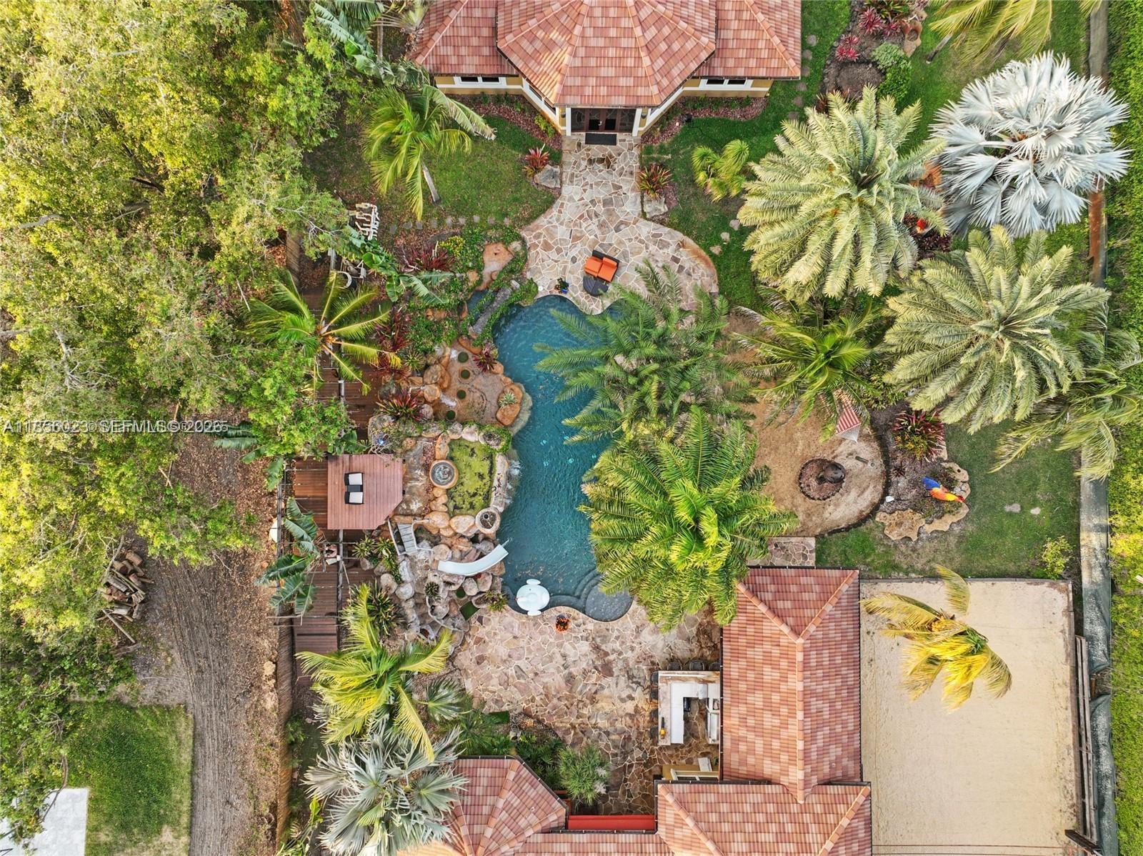 An aerial view of a backyard featuring a swimming pool, stone patio, and palm trees — 14503 SW 16th St, Davie FL 33325, DAVIE, FL