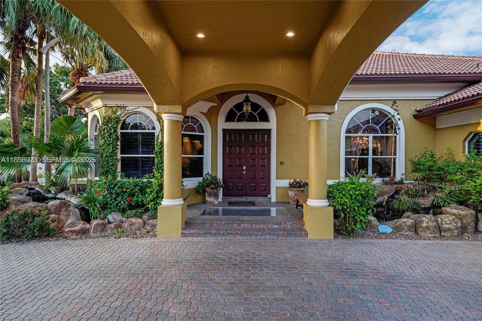 The exterior of a house features a covered entryway with columns and a brick driveway — 14503 SW 16th St, Davie FL 33325, DAVIE, FL