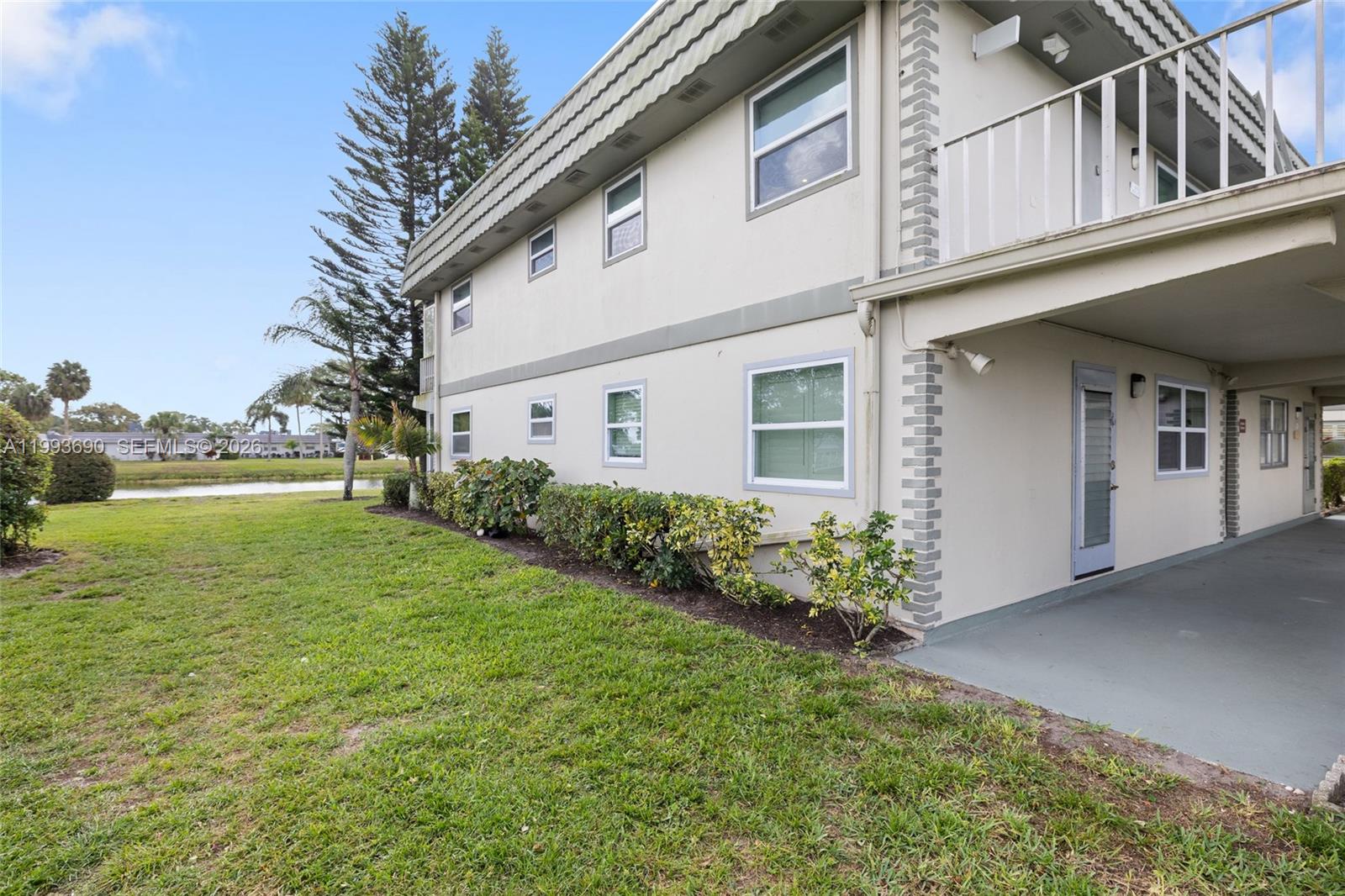 The exterior of a two-story residential building features a covered patio and a grassy lawn — 72 Monaco B # 72, Delray Beach FL 33446, DELRAY BEACH, FL