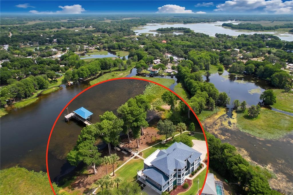 An aerial view shows a multi-story house with a blue roof and a private dock — 1360 S WATERVIEW DRIVE, INVERNESS, FL