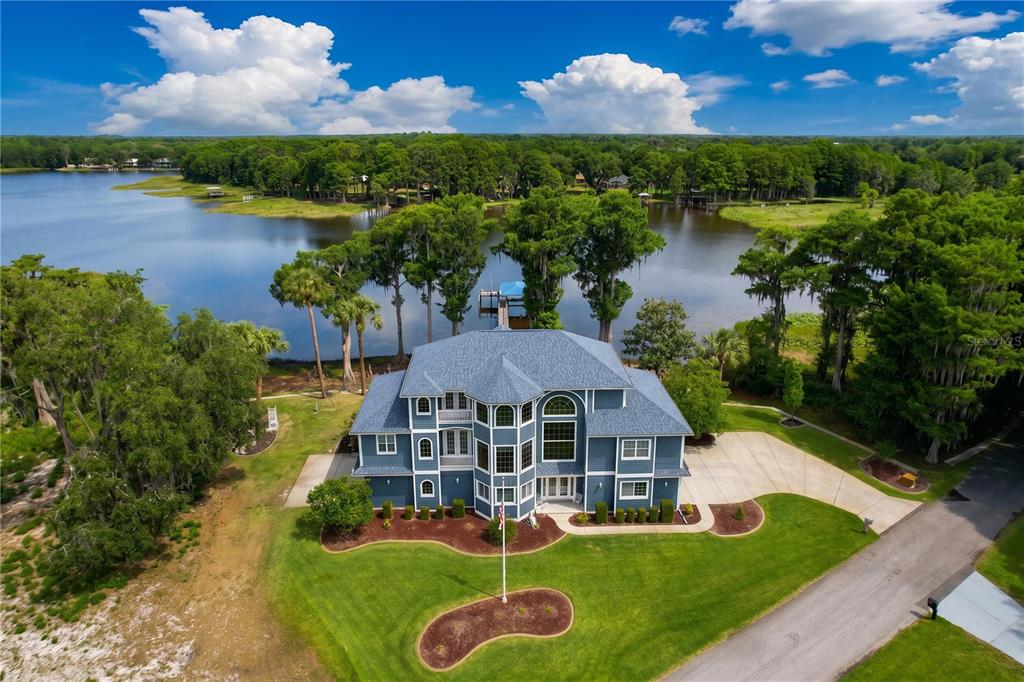 An aerial view of a large blue multi-story house situated on a lakefront lot — 1360 S WATERVIEW DRIVE, INVERNESS, FL