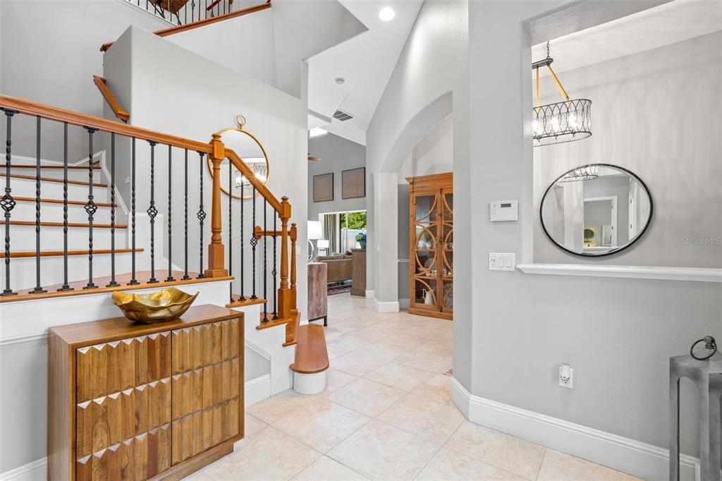 An entryway features a wooden staircase with iron railings, a console table, and tiled flooring — 429 2ND STREET S, SAFETY HARBOR, FL