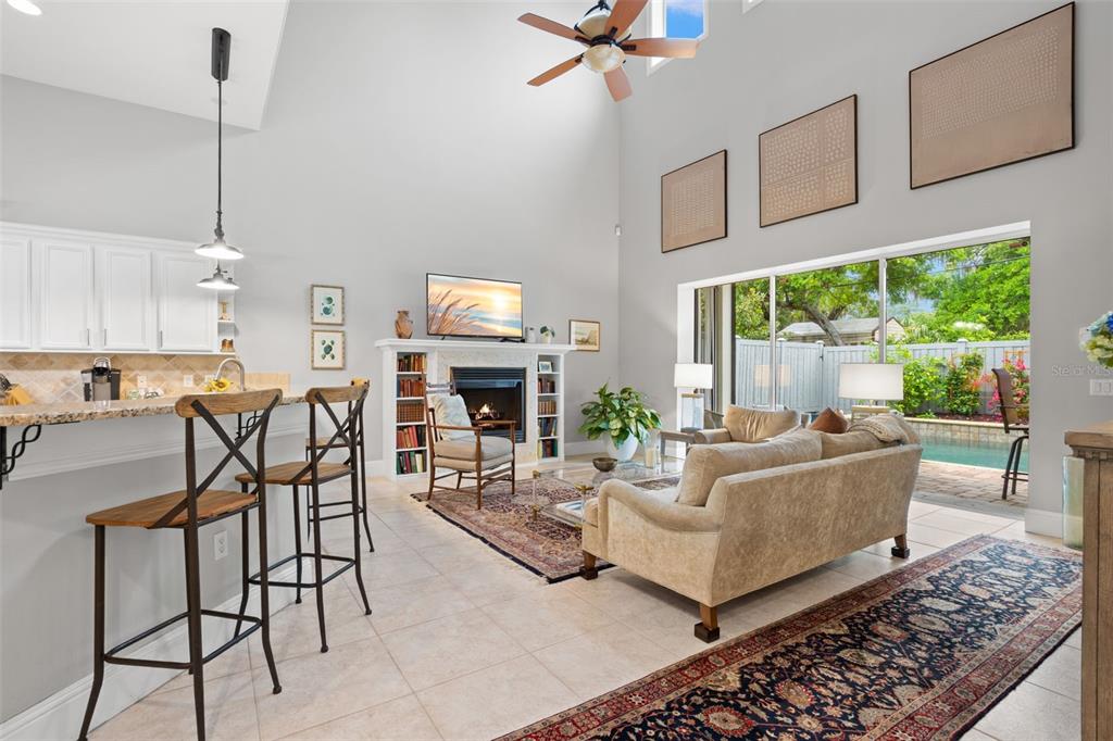 A living room with a fireplace, high ceilings, and a sliding door opening to a pool — 429 2ND STREET S, SAFETY HARBOR, FL
