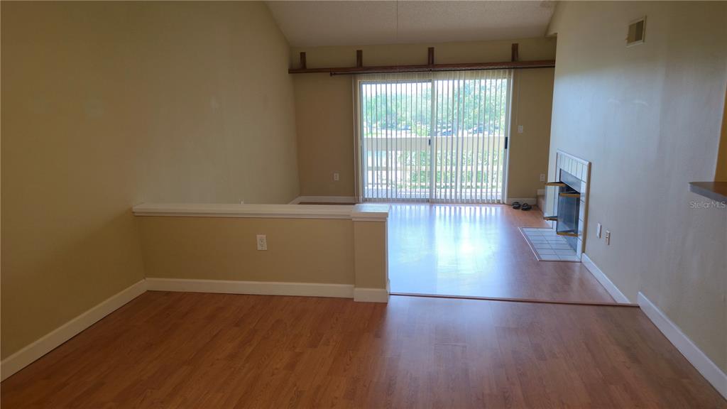 A living room with wood-look flooring, a fireplace, and a sliding glass door to a balcony — 115 112TH AVENUE NE UNIT 810, ST PETERSBURG, FL
