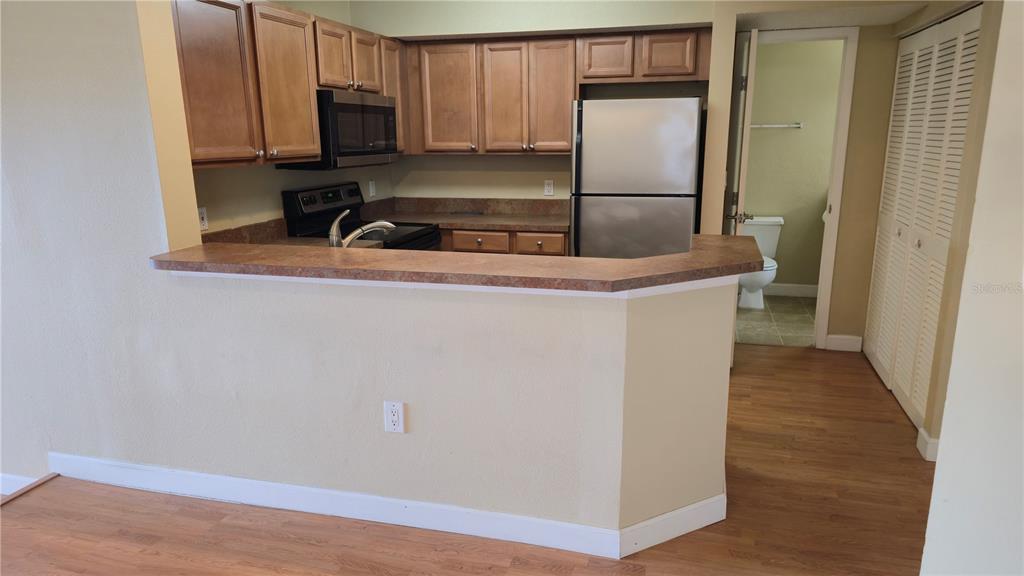 A kitchen with wood cabinets, stainless steel appliances, and a breakfast bar counter — 115 112TH AVENUE NE UNIT 810, ST PETERSBURG, FL