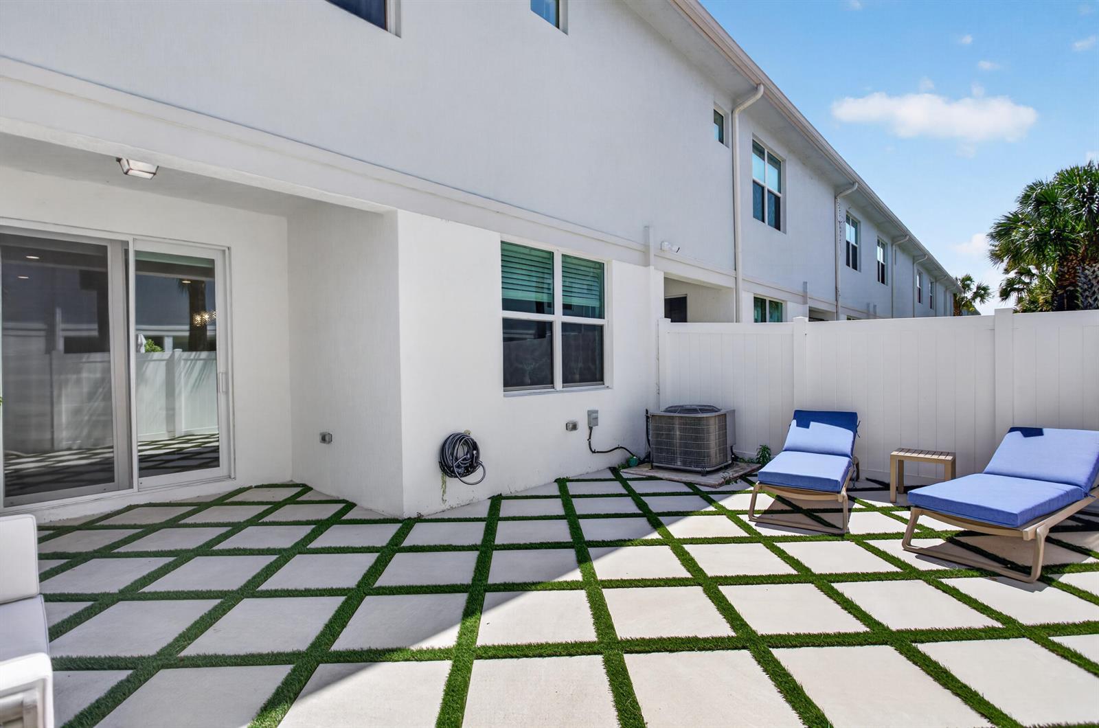 A patio features square concrete pavers with grass inlays, two lounge chairs, and a fence — 1835 Sandpiper Pointe Place, Deerfield Beach FL 33442, DEERFIELD BEACH, FL