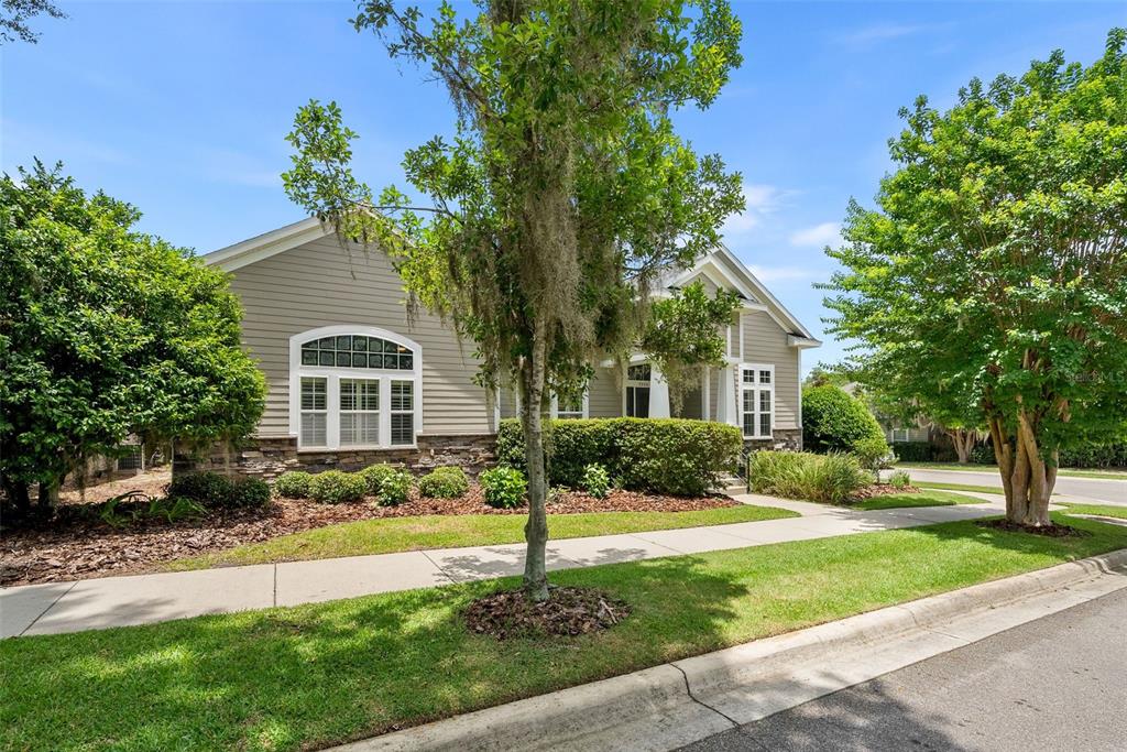 A single-story house with beige siding, stone accents, and a sidewalk in the front yard — 7220 SW 35TH ROAD, GAINESVILLE, FL