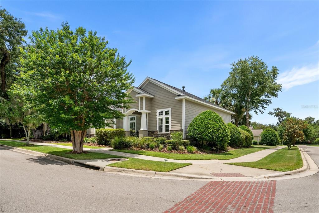 A single-story house with tan siding and a stone base sits on a corner lot — 7220 SW 35TH ROAD, GAINESVILLE, FL