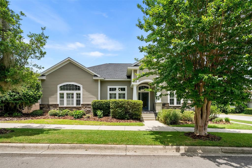 A single-story house with beige siding, stone accents, and a large tree in the front — 7220 SW 35TH ROAD, GAINESVILLE, FL