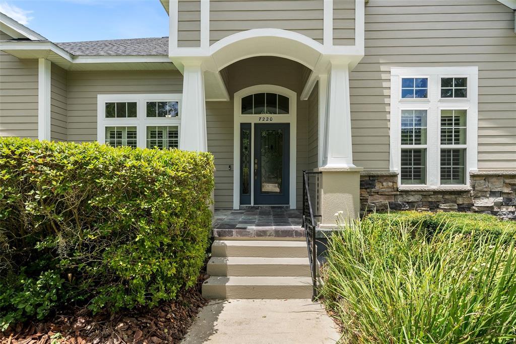 The exterior of a house features a covered entryway with steps, a blue door, and siding — 7220 SW 35TH ROAD, GAINESVILLE, FL
