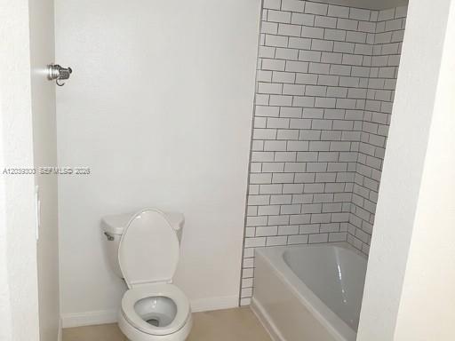 A bathroom features a white toilet next to a bathtub with white subway tile walls — 7446 Sugar Bend Dr # 0, Orlando FL 32819, ORLANDO, FL