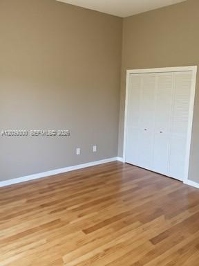 An empty room with light wood flooring, beige walls, and white louvered closet doors — 7446 Sugar Bend Dr # 0, Orlando FL 32819, ORLANDO, FL