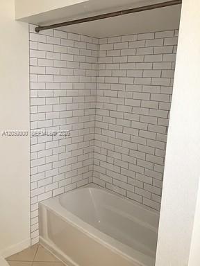 A white bathtub is surrounded by white subway tile walls and a shower curtain rod — 7446 Sugar Bend Dr # 0, Orlando FL 32819, ORLANDO, FL
