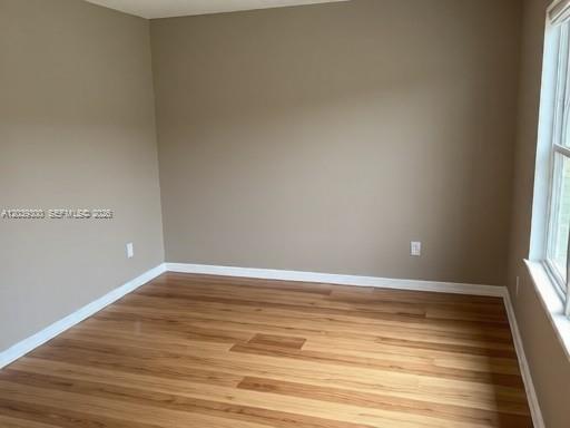 An empty room with light brown walls, wood-look flooring, and a window on the right — 7446 Sugar Bend Dr # 0, Orlando FL 32819, ORLANDO, FL