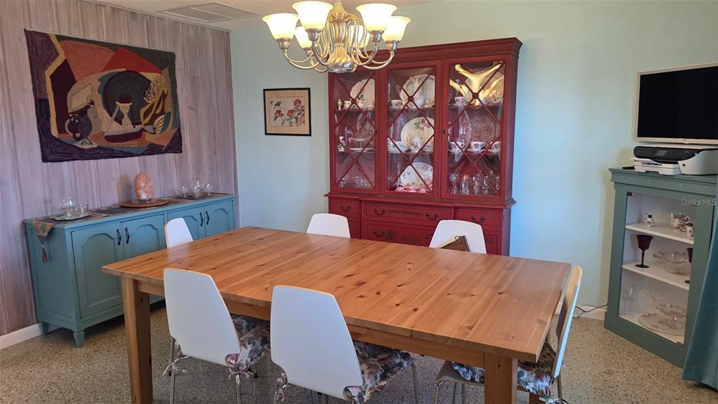 A dining room features a wooden table, white chairs, a red hutch, and blue cabinets — 707 JANE AVENUE, NEW SMYRNA BEACH, FL