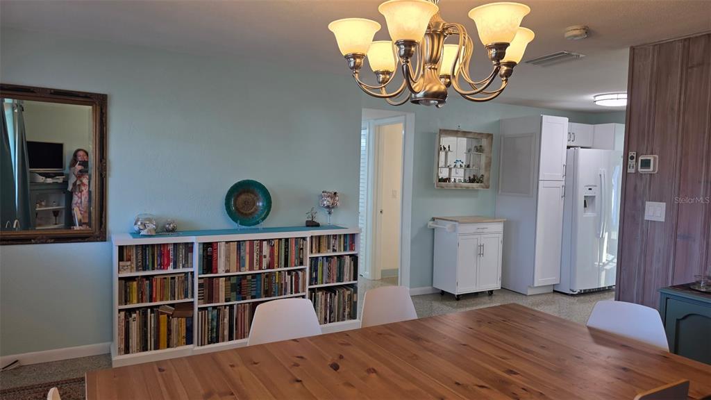 A dining area features a wooden table, a bookshelf, and a chandelier under light-blue walls — 707 JANE AVENUE, NEW SMYRNA BEACH, FL