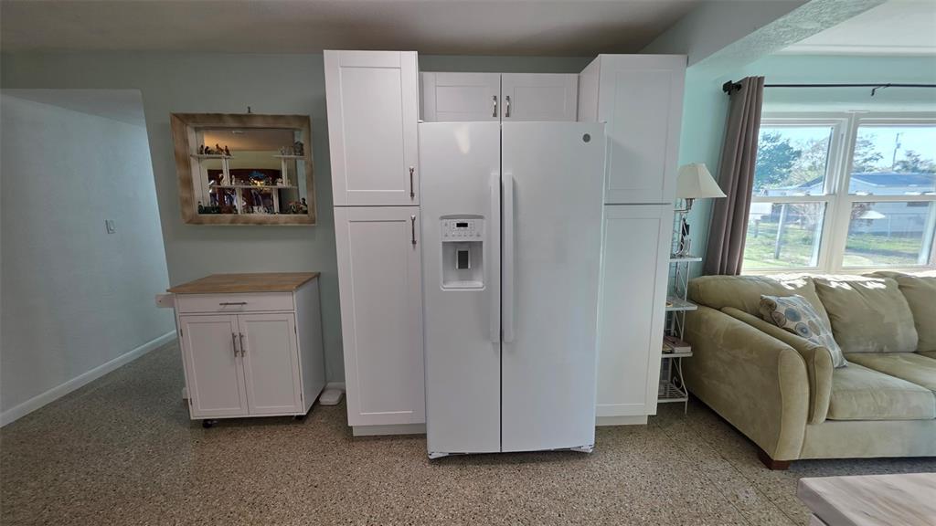 A white refrigerator is surrounded by white cabinetry in a room with terrazzo flooring — 707 JANE AVENUE, NEW SMYRNA BEACH, FL
