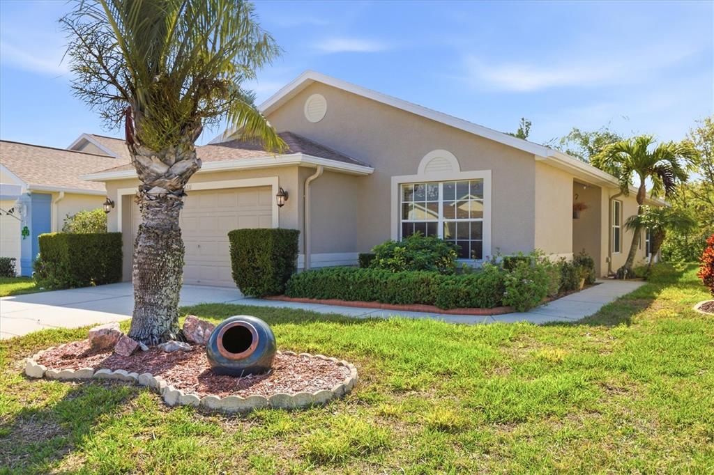 A single-story house with a beige stucco exterior, a garage, and a palm tree — 2211 PLEASANT HILL LANE, HOLIDAY, FL