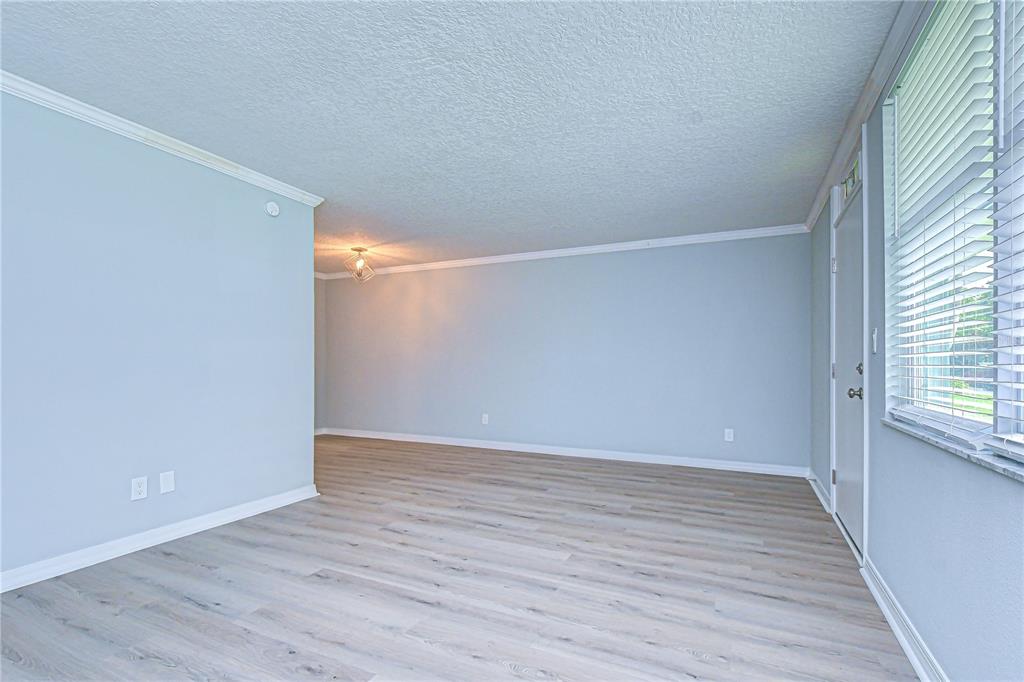 An empty room with light blue walls, wood-look flooring, and a window with blinds — 4720 LOCUST STREET NE UNIT 118, ST PETERSBURG, FL